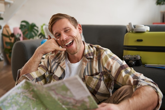 Free photo portrait of smiling tourist young man invited to go on vacation shows call me phone hand gesture