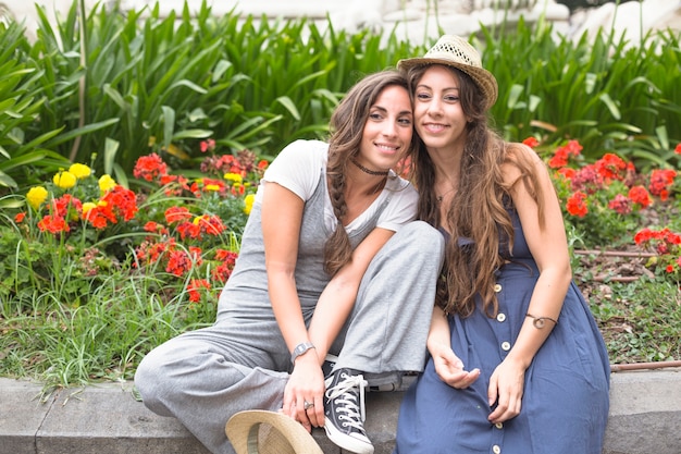 Portrait of smiling two female friends sitting in the garden
