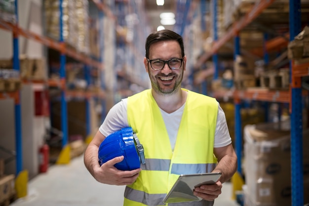 Free photo portrait of smiling warehouse worker with tablet standing in storage department