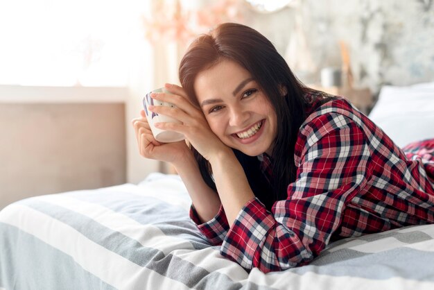 ベッドで朝を楽しむ笑顔の女性の肖像画