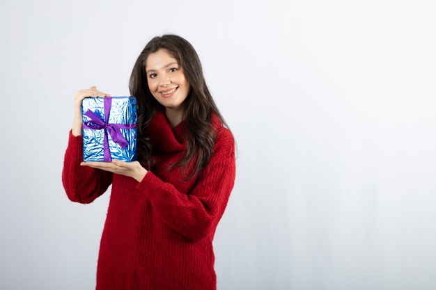 보라색 리본으로 크리스마스 선물 상자를 들고 웃는 여자의 초상화.