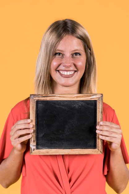 Portrait of smiling woman holding empty black slate