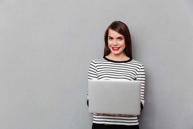 Free photo portrait of a smiling woman holding laptop computer