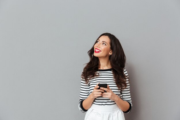 Портрет улыбающейся женщины, держащей мобильный телефон