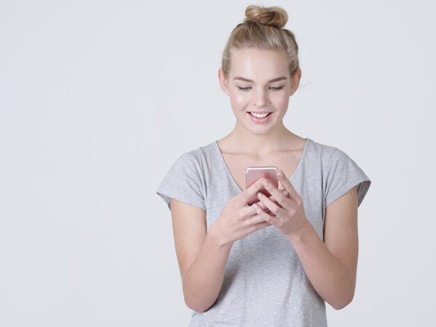 Portrait of a smiling woman is typing text message on mobile phone  - at studio