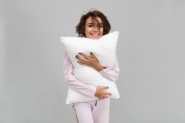 Foto gratuita ritratto di una donna sorridente in pigiama che tiene un cuscino