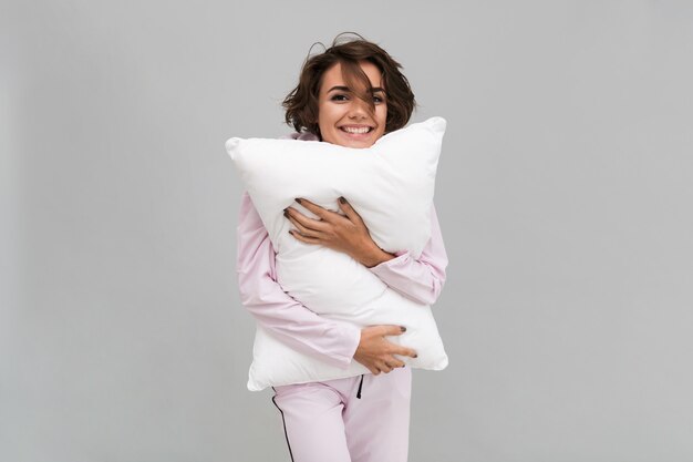 Portrait of a smiling woman in pajamas holding a pillow