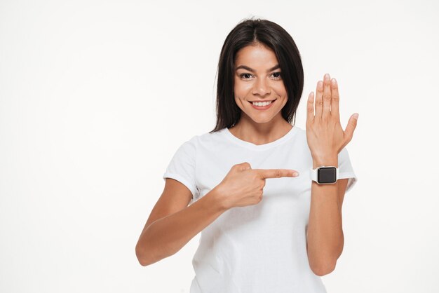 Портрет улыбающейся женщины, указывающей пальцем на умные часы