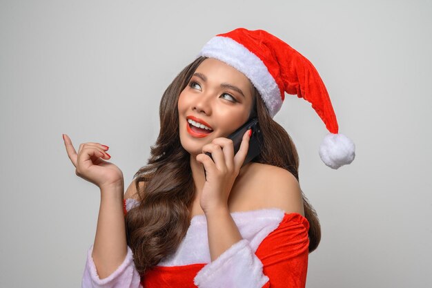 Portrait of smiling woman in red santa claus showing smartphone