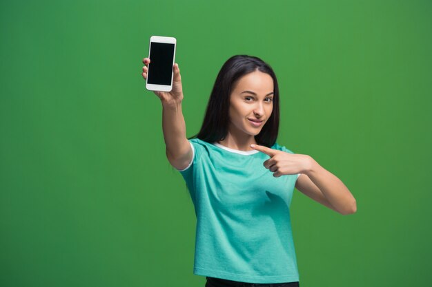 緑に分離された空白のスマートフォンの画面を示す笑顔の女性の肖像画