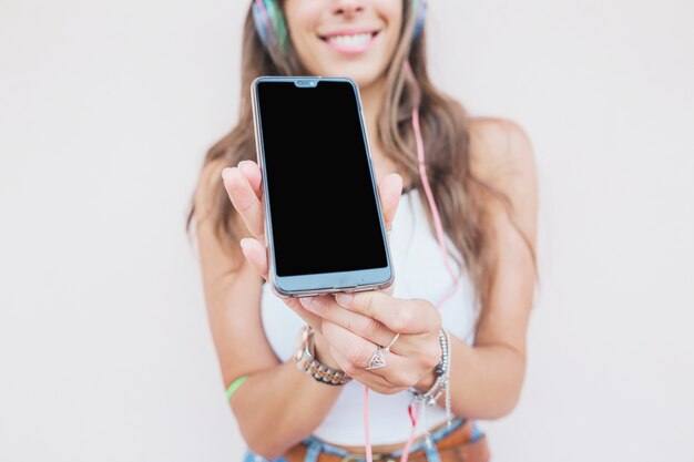 Portrait of smiling woman showing mobile screen on white background