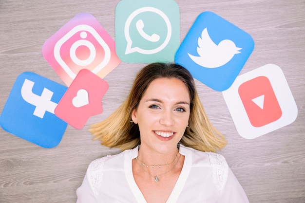 Free photo portrait of smiling woman standing in front of wall with social networking icons