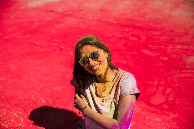 Portrait of a smiling woman standing over the red holi color powder