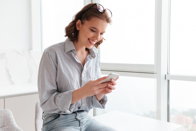 携帯電話でテキストメッセージを笑顔の女性の肖像画