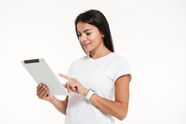 Портрет улыбающегося женщины с помощью планшетного компьютера стоя