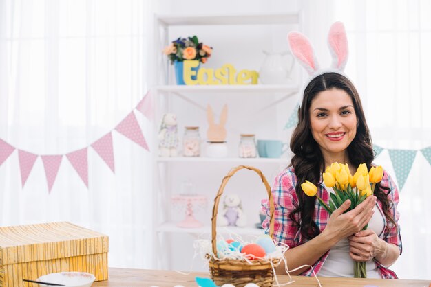 Portrait of a smiling woman wearing bunny ears holding tulips in hand