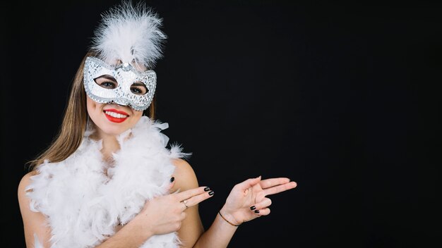 Портрет улыбающейся женщины в карнавальной маске показывать на белом фоне