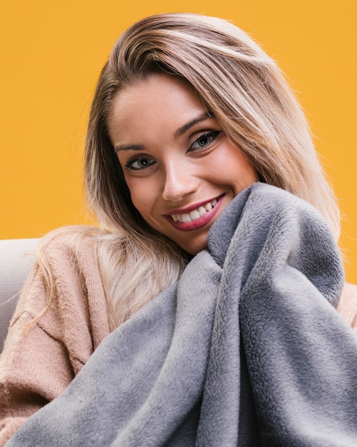 Foto gratuita ritratto della donna sorridente con la coperta che si siede sul sofà a casa