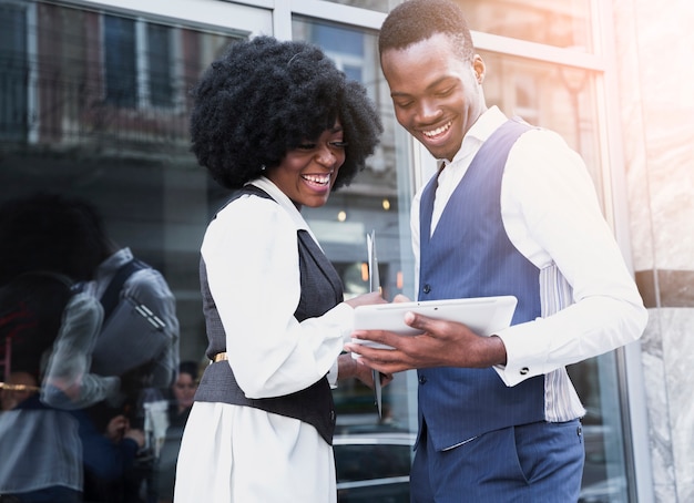Portrait of a smiling young african businessman and businesswoman looking at digital tablet