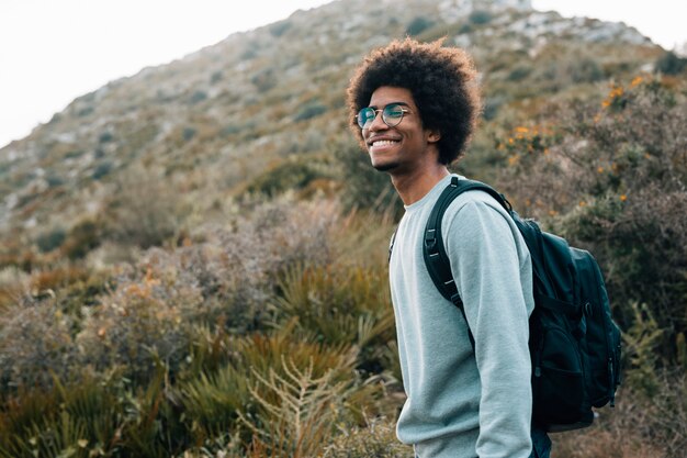 Портрет улыбающегося молодого африканского человека с его рюкзаком