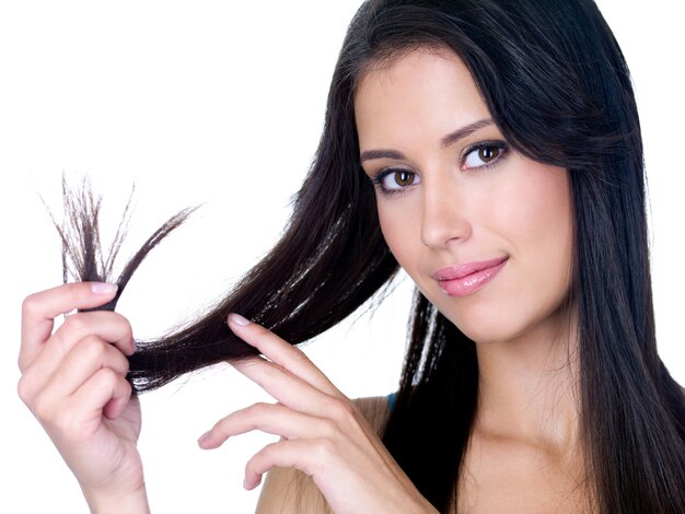 Portrait of smiling young beautiful woman holding ends of  her long brown hair - white