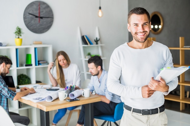 Free photo portrait of a smiling young businessman holding folder