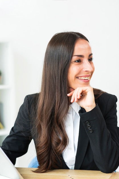 Free photo portrait of smiling young businesswoman sitting at office desk