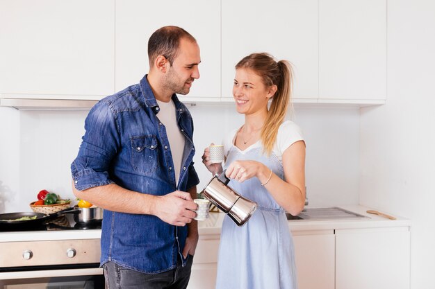 Portrait of smiling young couple drinking the coffee standing in the kitchen
