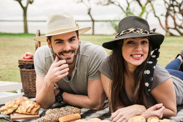 Портрет улыбающейся молодой пары, наслаждаясь на пикнике