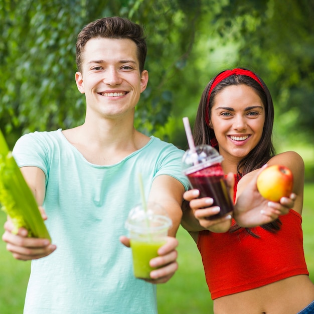 Foto gratuita ritratto di giovani coppie sorridenti che mostrano i frullati della mela e dell'avocado