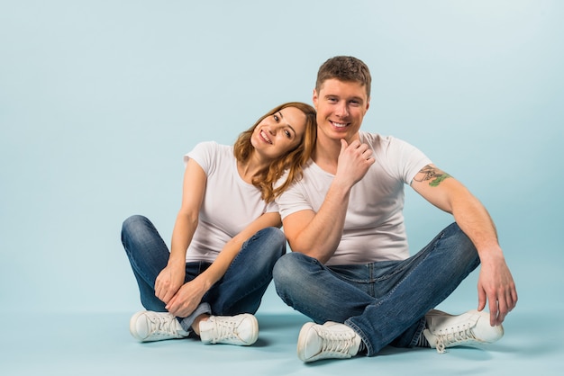 Портрет улыбающиеся молодые пары, сидя на синем фоне