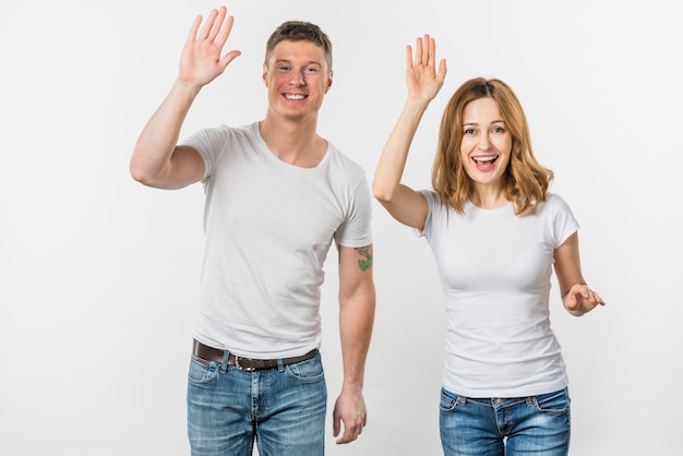 Portrait of a smiling young couple waving their hands looking to camera