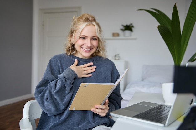Free photo portrait of smiling young cute woman holding notebook girl with laptop and planner in hands sits in