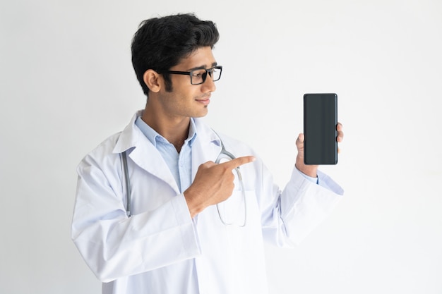 Portrait of smiling young doctor in glasses showing mobile phone.