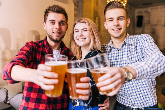 Portrait of a smiling young friends toasting the beer glasses