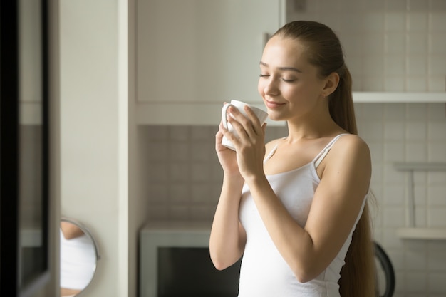 Portrait of a smiling young girl inhaling aroma of drink