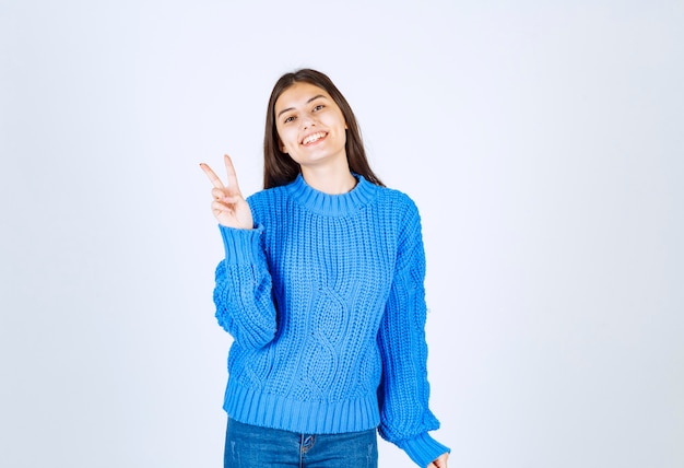 Portrait of a smiling young girl model showing victory sign.