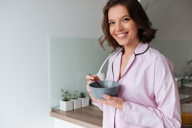 Portrait of a smiling young girl in pajamas having breakfast