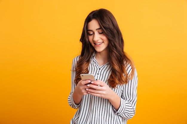 Ritratto di una ragazza sorridente che per mezzo del telefono cellulare