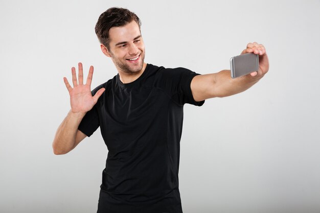 Portrait of a smiling young guy waving to camera