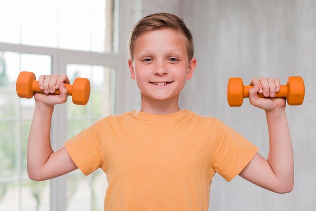 Portrait of a smiling young man holding dumbbell in hands looking at camera