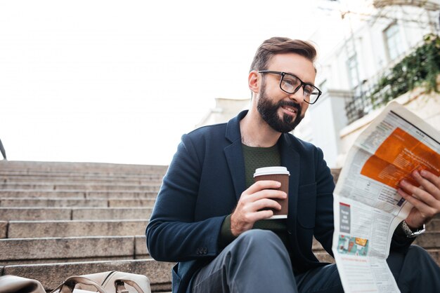 Portrait of a smiling young man reading newspaper