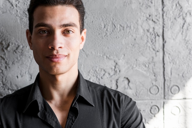 portrait of a smiling young man standing against wall
