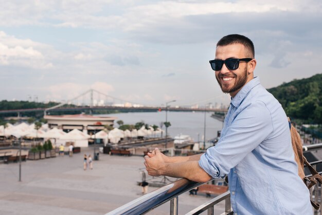 Portrait of smiling young man standing near railing looking at camera