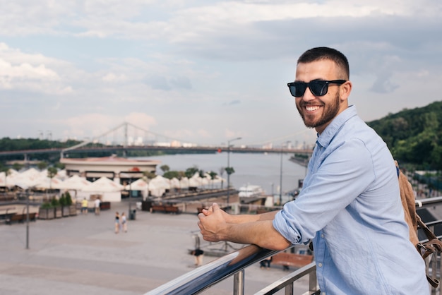 Portrait of smiling young man standing near railing looking at camera