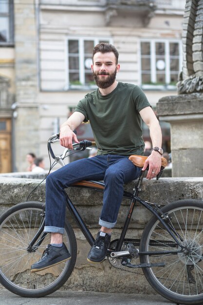 Портрет улыбающегося молодого человека с велосипедом в городе