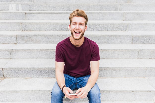 Портрет улыбающегося молодого человека со смартфоном