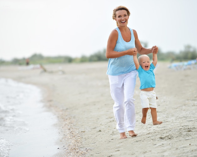 Портрет улыбающейся молодой матери с маленьким ребенком на пляже.