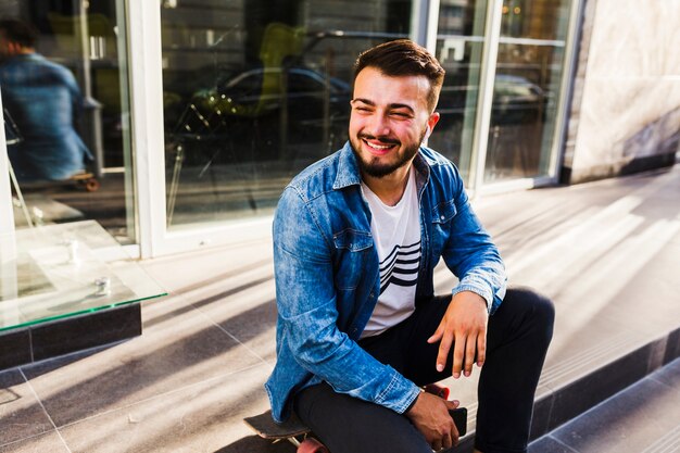 Portrait of a smiling young skateboarder sitting on staircase