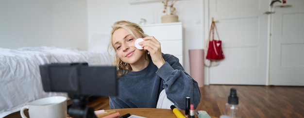 Free photo portrait of smiling young woman applies makeup shows beauty tutorial on video records vlog on